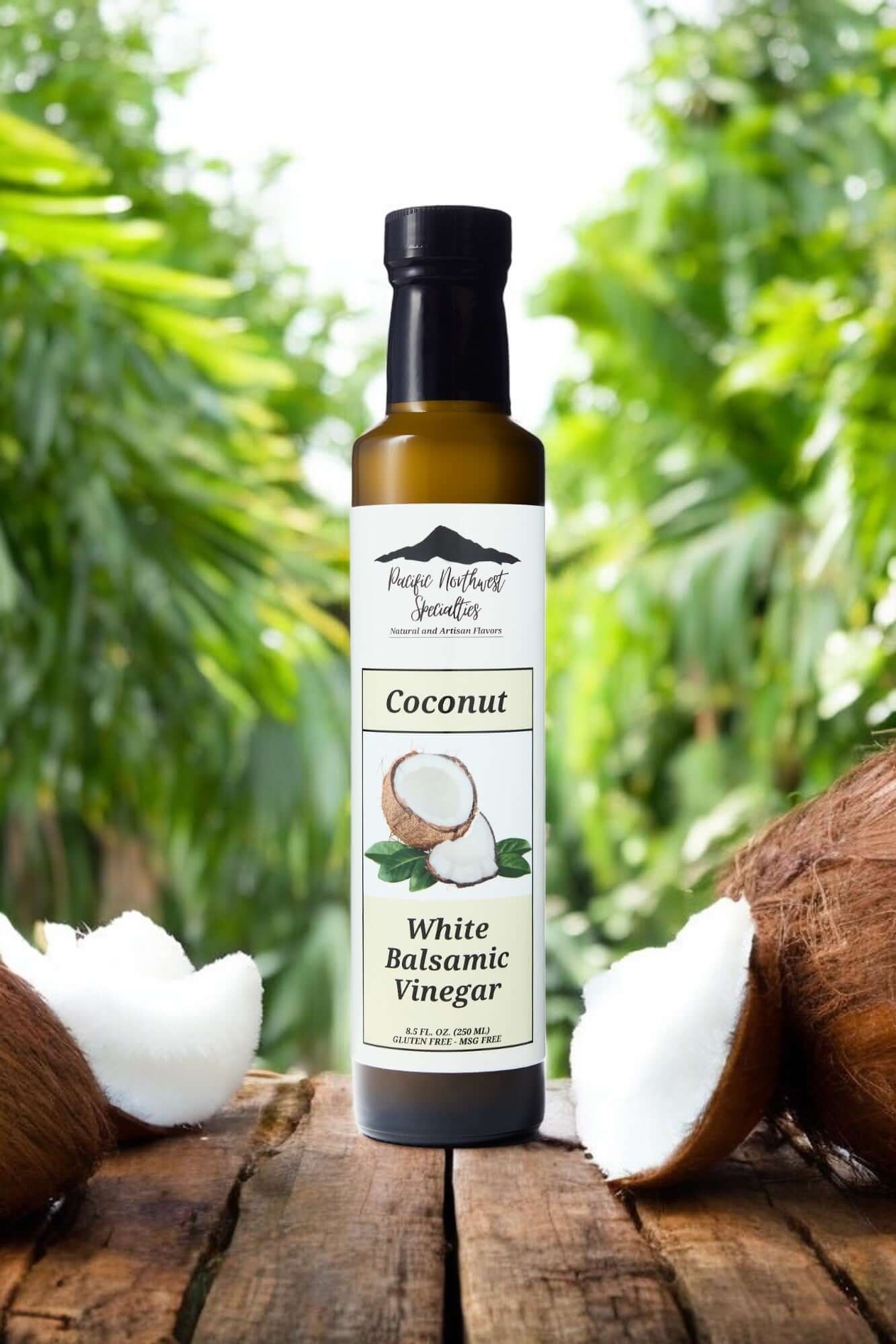 Coconut White Balsamic Vinegar bottle surrounded by fresh coconuts and tropical greenery. Perfect for dressings and marinades.