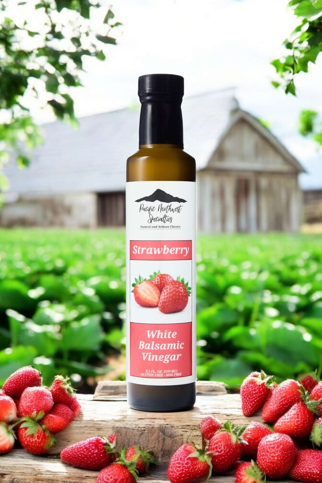 Bottle of Strawberry White Balsamic Vinegar surrounded by fresh strawberries in a scenic farm setting.